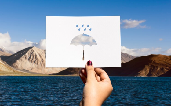 a hand holding a weather symbol of an umbrella and rain